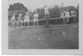 A group of children sitting on a fence

Description automatically generated